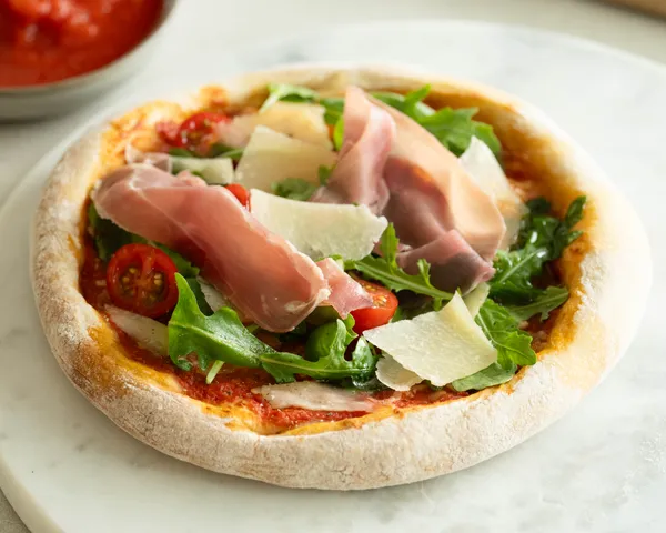 Pizza mit Parmaschinken, Rucola und Parmesan